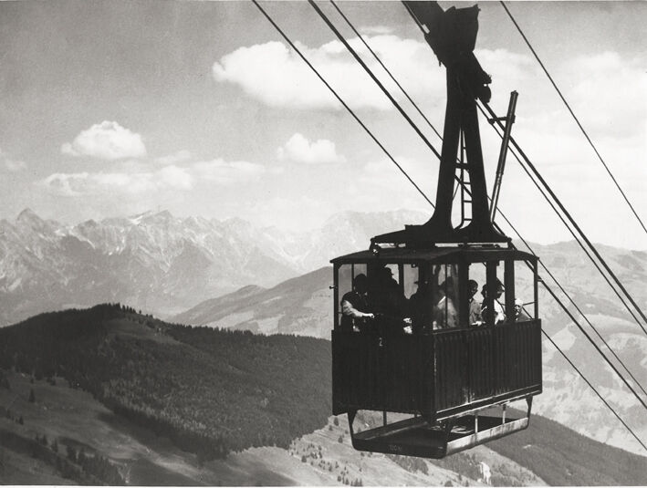Historische Seilbahn mit Passagieren in den Bergen.